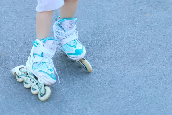 Benen van het meisje met witte rolschaatsen op asfalt buiten — Stockfoto