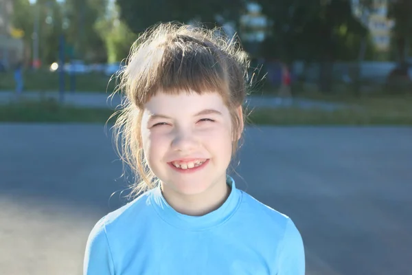 Ragazza in blu sorride sul parco giochi in estate giornata di sole, da vicino — Foto Stock