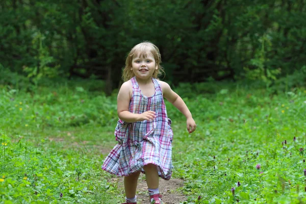 Smiling little blonde girl in dress runs at summer day in green — Stock Photo, Image