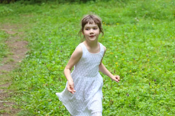 Souriante petite fille en robe blanche court le jour d'été dans le parc — Photo