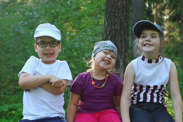 Three children sits, smile and grimace in summer — Stock Photo, Image