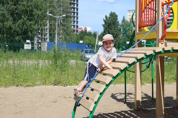 Happy little boy climbs on children playground at summer — Stock Photo, Image