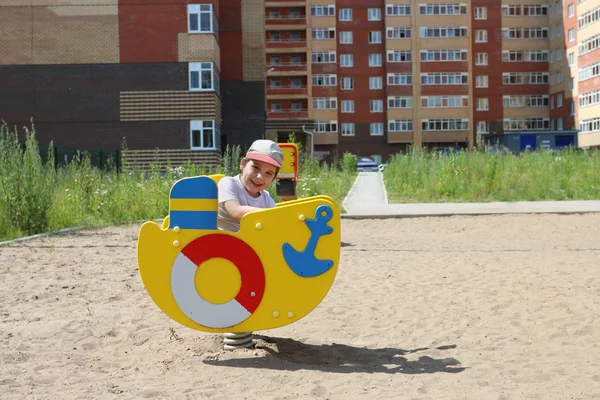 Happy little boy in cap swings on wooden ship — Stock Photo, Image