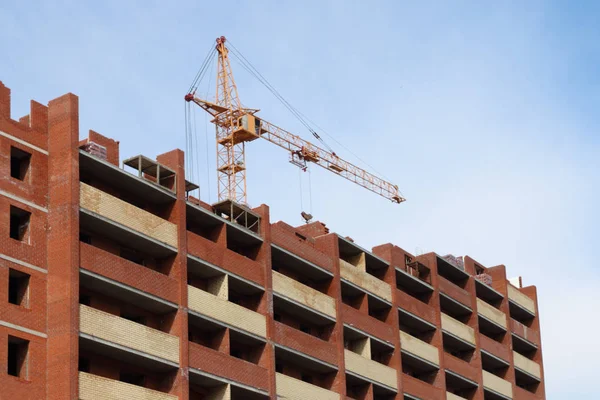 Arbeitskran und Wohnhaus aus rotem Ziegel im Bau — Stockfoto