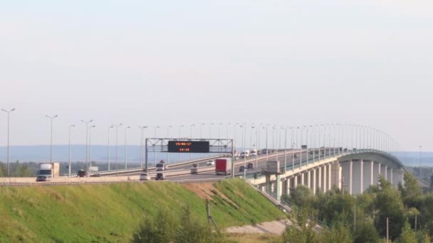 Coches, autobuses y camiones se mueven en el puente con el tablero de tiempo en el día de verano, lapso de tiempo — Vídeos de Stock