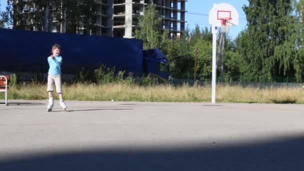 Patines de niña en el patio de recreo cerca de edificios en construcción en el día soleado — Vídeo de stock