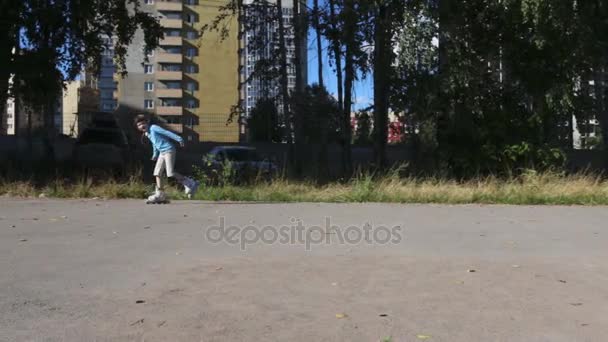 Ragazza felice pattini a rotelle sul parco giochi vicino a edifici in costruzione nella giornata estiva — Video Stock