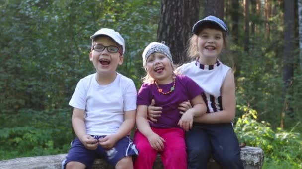 Tre barn leende, omfamning och grimas i sommaren park — Stockvideo