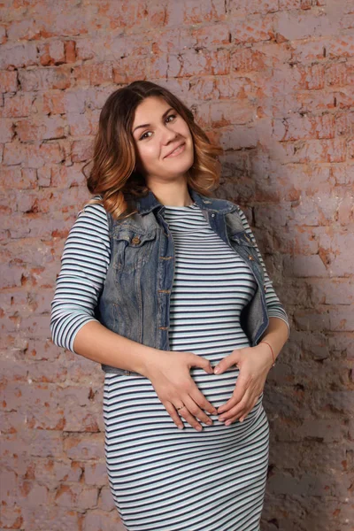 Beautiful pregnant woman in striped dress, jacket is standing — Stock Photo, Image