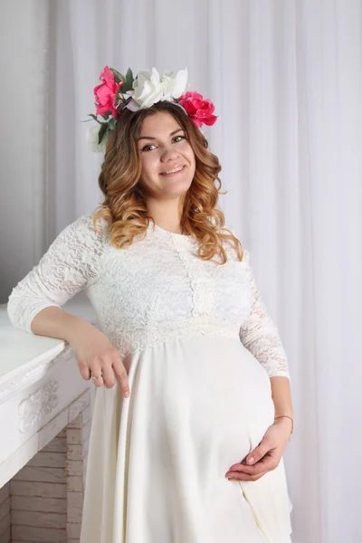 Beautiful pregnant woman in white dress and wreath in her hair — Stock Photo, Image