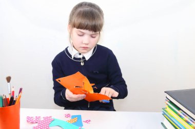 Tablo w üzerinde renkli kağıttan makasla liseli kız kesiliyor