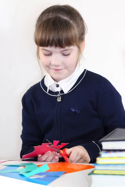 Sorridente ragazza della scuola si ritaglia con le forbici di carta colorata su — Foto Stock