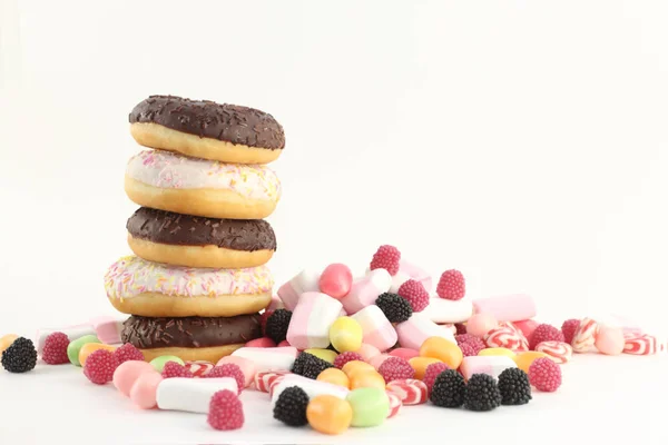 Vijf donuts, heldere snoepjes en marshmallows op witte ondergrond — Stockfoto