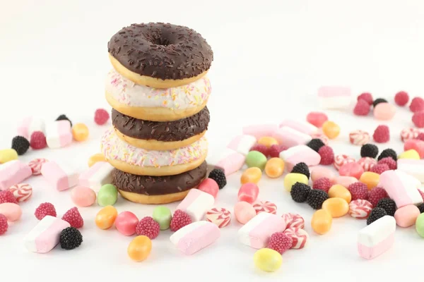 Pět koblihy, mnoho světlé bonbony a marshmallows na bílém povrchovým vodám — Stock fotografie