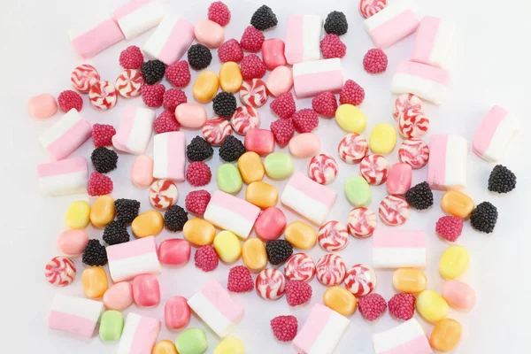 Muitos doces doces e brilhantes e marshmallows na superfície branca — Fotografia de Stock
