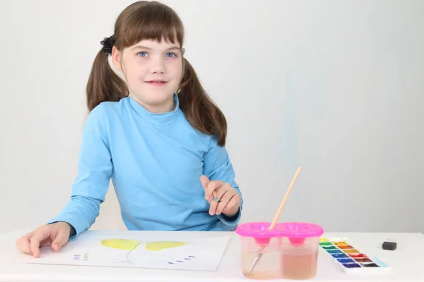 微笑的女孩水彩画蝴蝶在桌在白色房间 — 图库照片