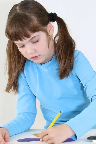 Menina feliz pinta borboleta aquarela com lápis na mesa em w — Fotografia de Stock