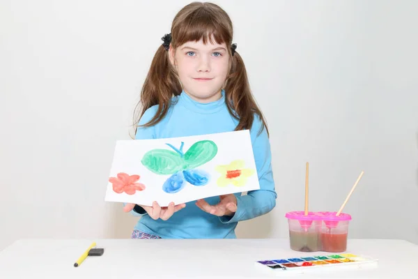 Sorridente bella ragazza mostra immagine con farfalla dopo watercolo — Foto Stock