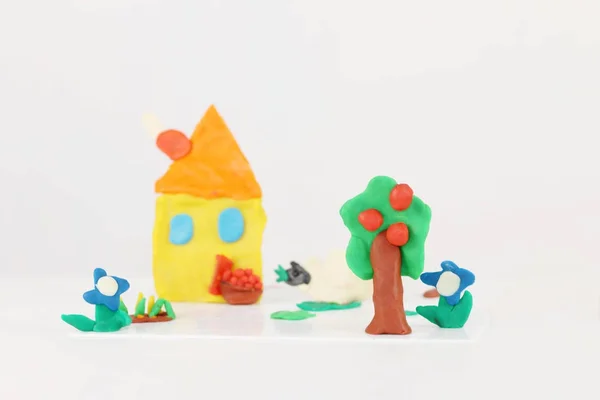 Casa lucente, pecore, fiori, albero da plastilina su tavola bianca — Foto Stock