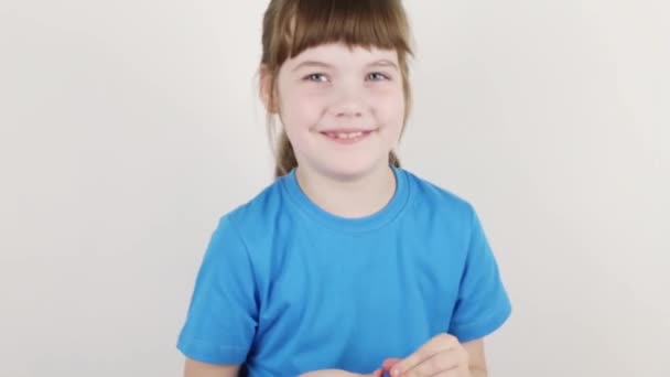 Mooi meisje in blauwe mallen huis vanaf plasticine op witte tafel in witte kamer — Stockvideo