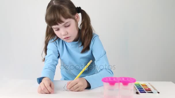 Hezká dívka v modrém akvarel maluje motýl na stole v bílé místnosti — Stock video