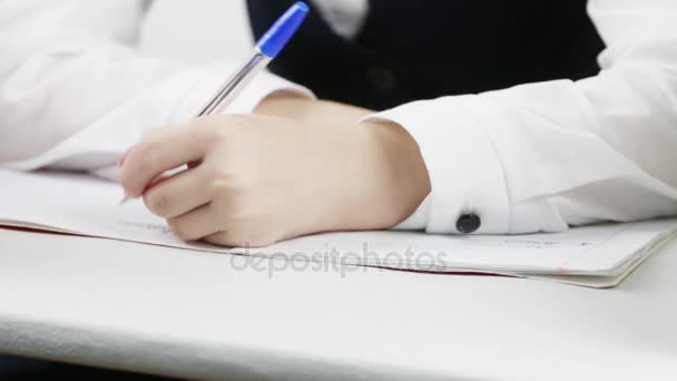 Ręka uczennica pisania w książce ćwiczeń przy stole, zbliżenie — Wideo stockowe