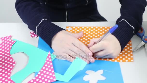 Hands of girl draws flower on colored paper and cuts for crafts, closeup — Stock Video