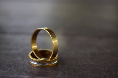 İki alyans, ahşap zeminde altın ve gümüş.