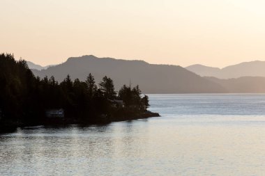 Ketchikan Alaska 'nın tepesinde yükselen güneş yumuşak ağaçlarla kaplı dağlar