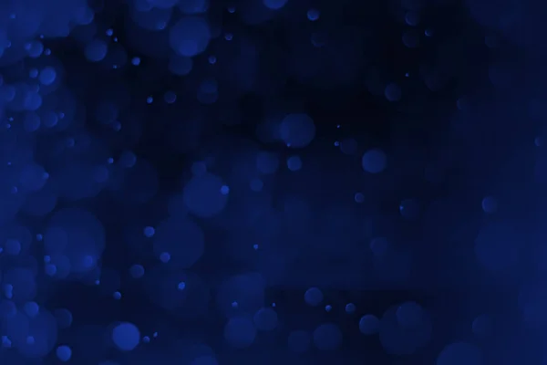 Bokeh luz azul em um fundo preto para o backgro de Natal — Fotografia de Stock