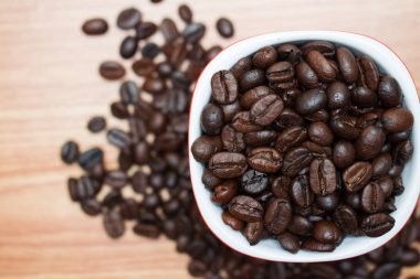 Kahve fincanındaki kahve çekirdekleri eski ahşap arka planda ve ince zekada.