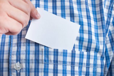 Ekose bir gömleğin üstünde kartvizit tutan bir el resmi..