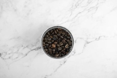 Kahve çekirdekleri mermer zeminde cam bir kavanozda.