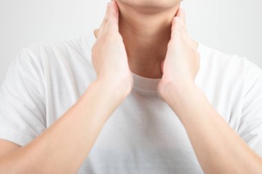 Asyalıların boğazı ağrıyor. İki elinle dokunarak.