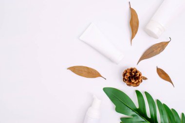 Beyaz arka planda yaprakları olan doğal cilt bakım kremi