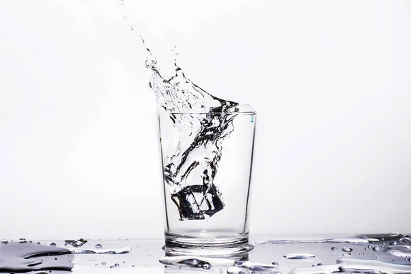 Вода в склянці з розбризкуванням води на білому тлі — стокове фото