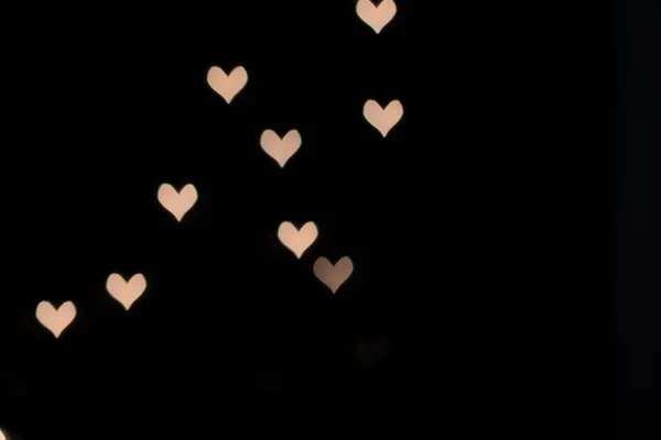 Heart-shaped bokeh from orange lights on a black background — 스톡 사진