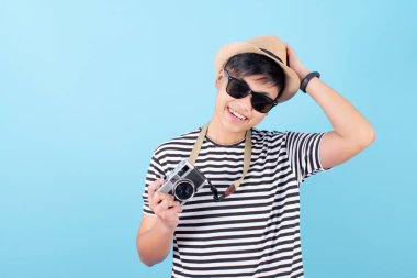 Asian tourists wearing t-shirts are holding a film camera on a b