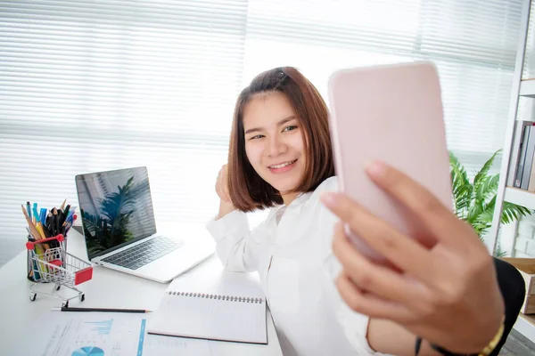 Una mujer de negocios asiática se está tomando una selfie para tomar una foto en el —  Fotos de Stock