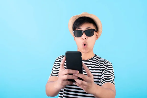 Egy fiatal ázsiai utazó megdöbbent egy okostelefonon egy kék csődörön. — Stock Fotó