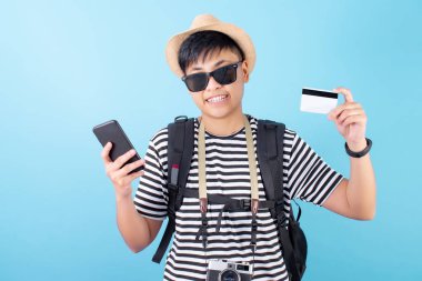 Yazlık giysiler giyen Asyalı turistler, mavi arka planda kredi kartıyla akıllı telefonlarıyla alışverişin keyfini çıkarıyorlar..