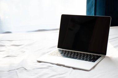 Bilgisayar sabah yatağın üzerinde yumuşak güneş ışığı büyük pencerenin yanında..