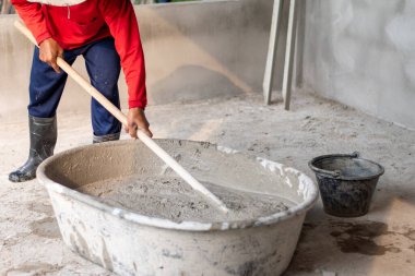 İnşaat işçileri inşaat sahasına duvar örmek için çimentoyu karıştırıyorlar..