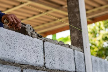Dış duvar inşa etmek için çimento kullanan bir inşaat işçisinin elleri yakın plan..