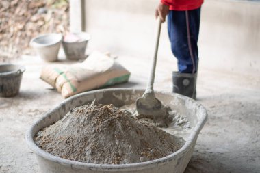 Depoda çimento ve kum var. İnşaat işçileri çimentoyu karıştırıyor.