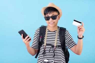 Asyalı turistler mavi arka planda yer ayırtmak için kredi kartları ve akıllı telefonlar kullanıyorlar..