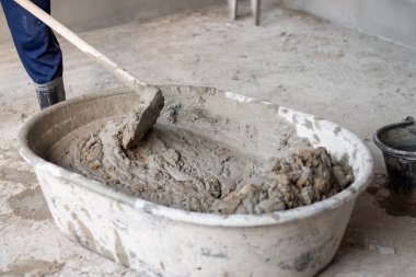 İnşaat işçileri çimento ve kumu ev inşa ekipmanlarıyla karıştırıyor. Ev inşa endüstrisi konsepti