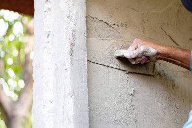 Eve duvar örmek için sıva yapan işçilerin ellerini kapatıyoruz. Ev inşa kavramı.