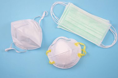 Mavi arka planda üç koruyucu maske, bir sürü maske. Üst görünüm.