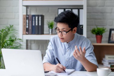 Genç Asyalı evde toplantı yapmak için video çekiyor. İş ve Teknoloji Konsepti.
